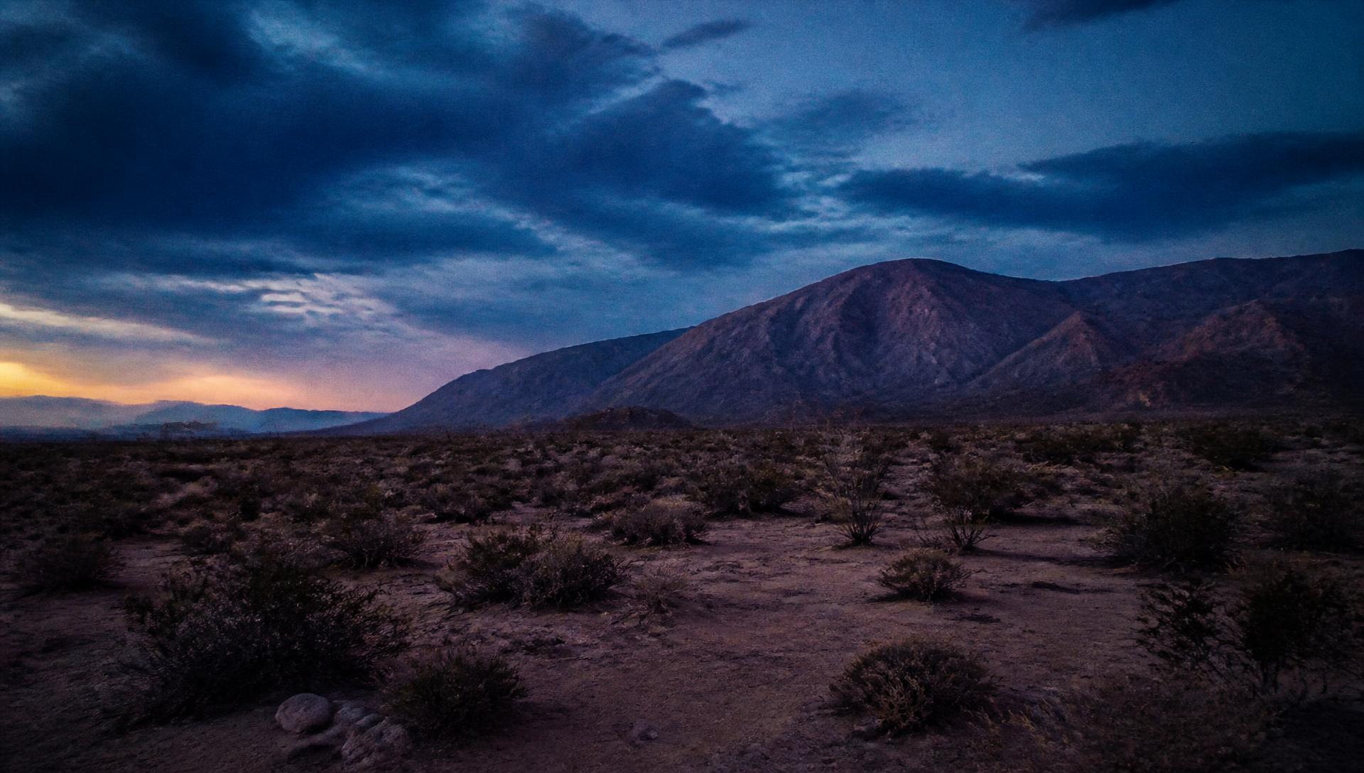 Desert landscape at dusk under a storm blue sky