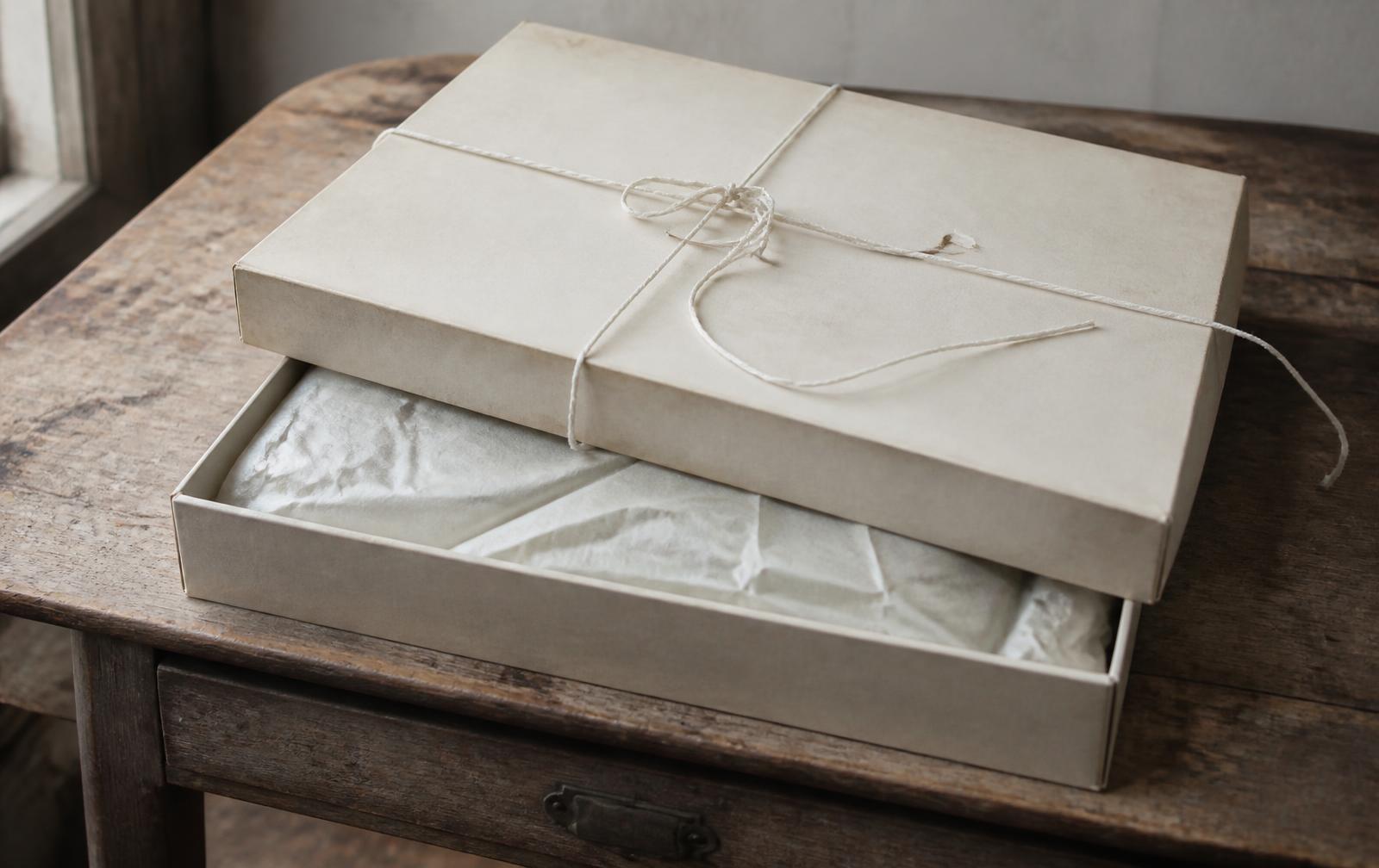 Off-white archive garment box tied with cotton twine on a wooden table